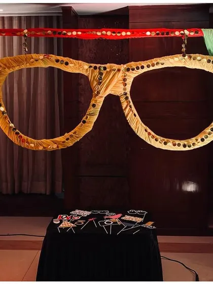 A fun photo booth prop with oversized glasses and directional signs, perfect for a quirky Mehendi party.