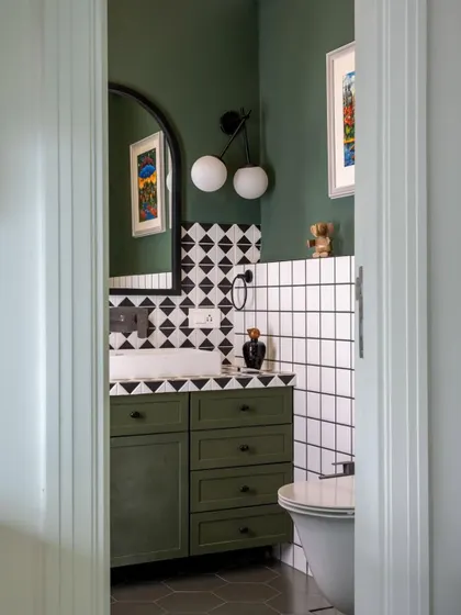 A bathroom in our 'Inde Blue' project, seen through a doorway. The design uses a palette of deep green, black, and white, with a mix of geometric and subway tiles to create a look that is graphic, modern, and soulful.