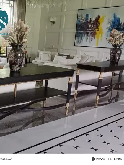 A pair of elegant console tables with a dark finish and delicate gold-accented legs. These pieces add a touch of sophistication behind a sofa or against a wall in a grand living room.