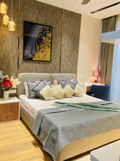 A full view of a bedroom with a dark, textured accent wall and gold metal inlays. The grey upholstered bed and plush pillows create a comfortable and sophisticated retreat.