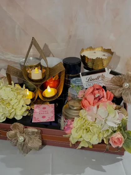 The Lotus Lit Hamper is designed to brighten anyone's day. It features a decorative lotus tea light holder, premium coffee and tea, mithai, and other gourmet snacks, all arranged in an elegant leatherette tray.