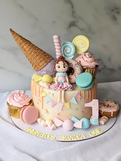 Biba's sweet one! This pastel candyland cake was a dream to make for a first birthday. It's overloaded with an ice cream cone, donuts, macarons, and a custom figurine.