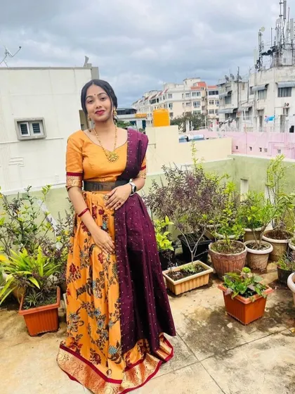 A client wearing a floral print lehenga with a contrasting maroon dupatta and a simple mustard blouse.