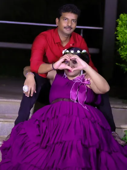 A sweet family maternity photo, with the couple and their son sitting on outdoor steps, making a heart shape with their hands.