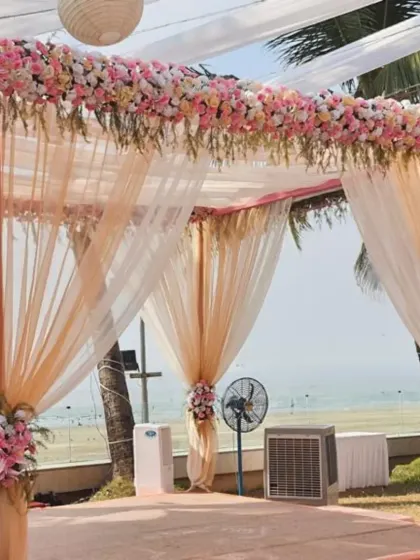 A closer look at a pastel peach and pink mandap. The combination of sheer drapes and thick floral arrangements on the pillars and roof creates a design that is both delicate and grand.