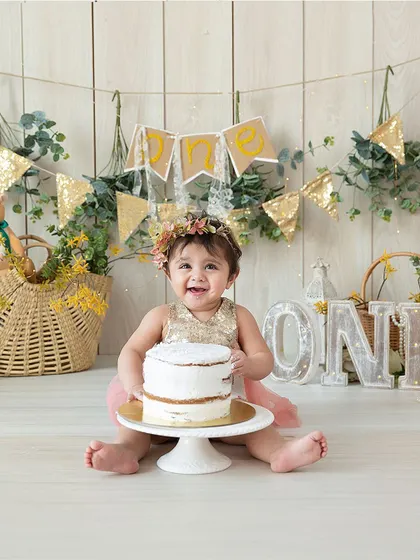 A happy smile before the smashing begins. This portrait captures the birthday girl with her cake in a beautiful, rustic setup with gold and yellow accents.