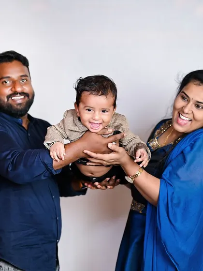 A fun and candid family photo, with the parents lifting their laughing baby. These playful moments are just as important as the posed ones.