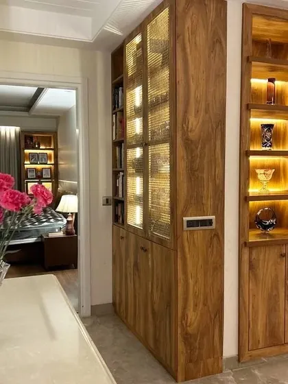 A full view of the corridor cabinetry, showing how we integrated both book storage and display niches. The warm, ambient lighting within the shelves creates a welcoming and sophisticated atmosphere.