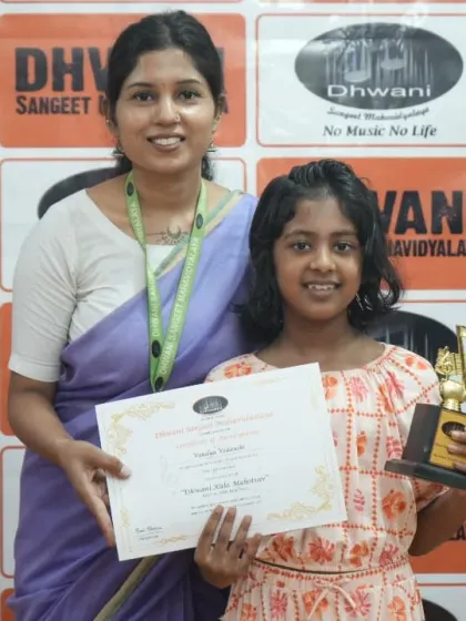 A faculty member presents an award to a young student, celebrating her performance.