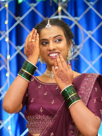 The right backdrop makes every photo special. Here, a client poses against a blue curtain with fairy lights, highlighting her henna and traditional attire.