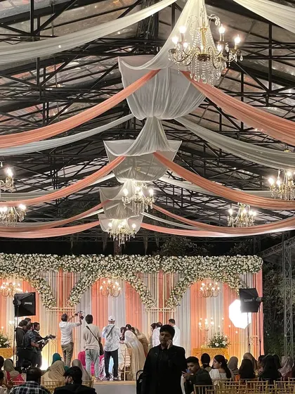 A beautifully decorated wedding hall with elegant draping and chandeliers. This is the kind of grand setting we can help arrange for your special day.