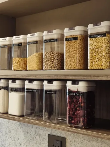 Decanting pantry items like dals, grains, and flours into clear, uniform containers creates a clean, organized look and helps you see your stock at a glance.