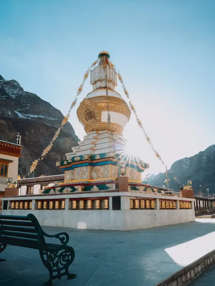 Images of the colorful Gue Monastery against the backdrop of snow-dusted mountains. The photos capture the intricate details of the stupa and the traditional Tibetan architecture.
