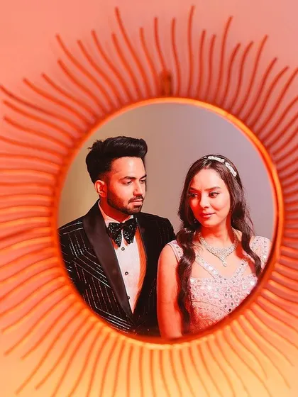 A creative portrait using a sunburst mirror to frame the newly engaged couple. This unique composition adds an artistic touch to their engagement photos while beautifully capturing their formal attire.