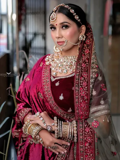 A poised and elegant portrait of the bride. Her hands are gently clasped, and the focus is on her complete look, from the heavy jewellery to the detailed embroidery of her outfit.