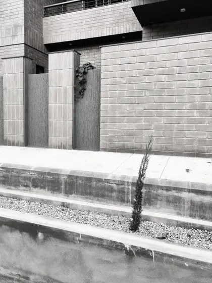 A close-up of the compound wall in black and white, showing the texture of the brickwork and the simple, clean lines of the design.
