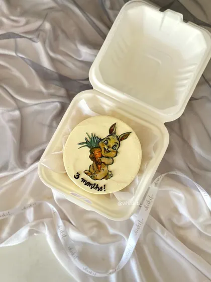 A hand-painted bento cake of a bunny holding a carrot to celebrate a 3-month milestone. The detailed artwork makes this mini cake extra special.