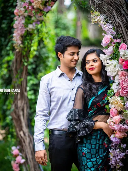 A classic portrait of a couple framed by a stunning floral arch.