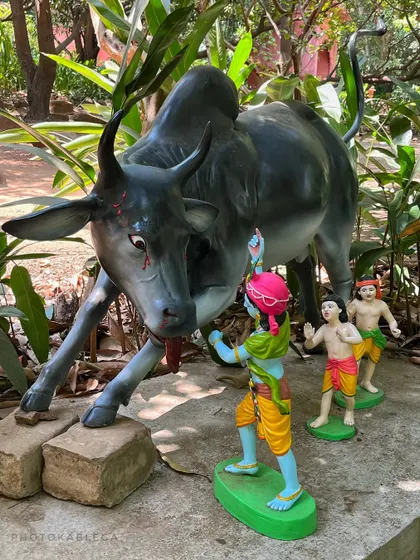 A colorful diorama depicting a young Krishna in a playful confrontation with the bull demon Arishtasura.