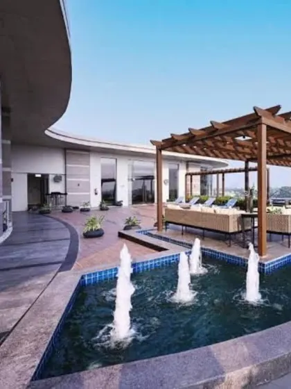 A view of a recently completed hotel project, showcasing a large water feature alongside a spacious terrace lounge area under a wooden pergola, designed for relaxation and events.
