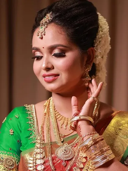 A graceful pose from bride Jaswitha. This close-up highlights her soft, shimmering eye makeup, perfectly defined brows, and the intricate details of her traditional gold jewellery.