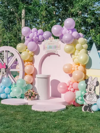 Welcome to "Anayaland". This pastel Disney-themed first birthday features a custom-arched backdrop, a soft rainbow balloon garland, and character cutouts, creating a magical world for the birthday girl and her little guests.