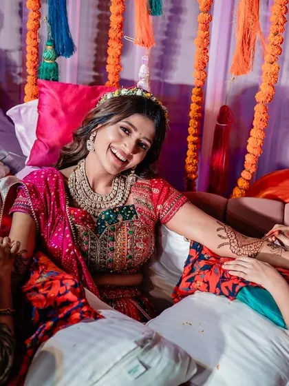 The bride smiles as her Mehendi (henna) is applied, a beautiful and significant pre-wedding ritual.