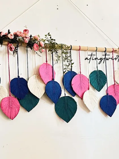 For a bolder look, this leaf wall hanging combines vibrant pinks and deep blues with natural white. The floral accents add an extra touch of elegance.