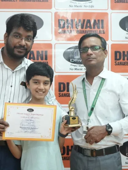 Two teachers proudly present an award to their dedicated student.