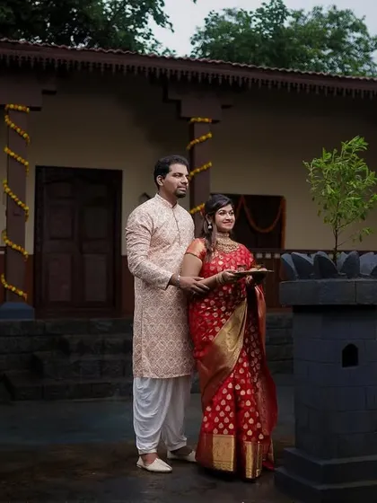 A couple performing a traditional ritual with a tulsi plant in the courtyard of a wada, beautifully capturing a moment of cultural significance.