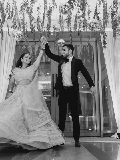 A beautiful black and white shot of the couple's first dance. The bride's twirling lehenga and their joyful expressions create a dynamic and timeless image.