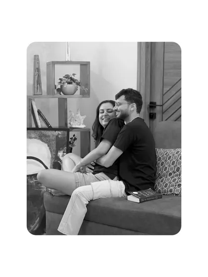 A sweet, candid black and white shot of the couple cuddling on a sofa, capturing a simple, everyday moment of love.