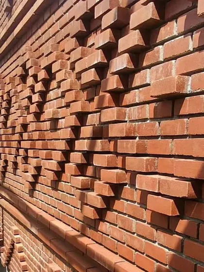 The angled sunlight creates sharp shadows, emphasizing the depth and complexity of the handcrafted brick pattern.