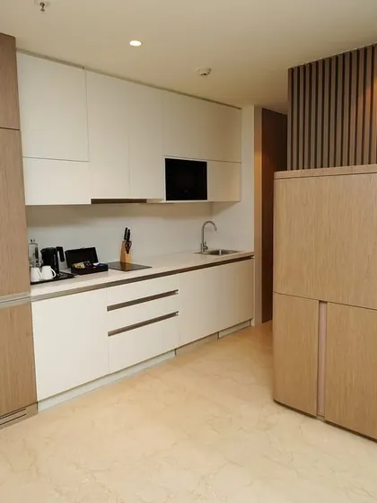 The suite's minimalist kitchenette, showcasing sleek, integrated appliances and smart, space-saving cabinetry design. This is essential for serviced apartments and extended-stay hotels.