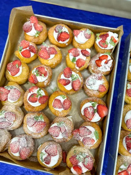 A mix of strawberry cream and raspberry crumble mini bombolinis, dusted with powdered sugar.