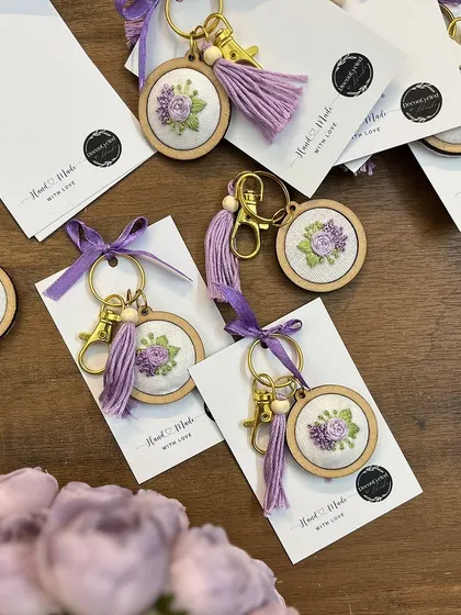 A close-up of the handmade embroidered keychains that were part of the baby announcement gift set. These delicate, personalized favors are a beautiful keepsake for friends and family.
