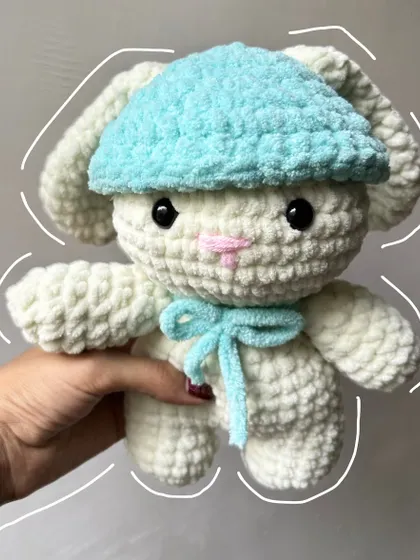A super soft and cuddly crochet bunny plushie with a cute blue hat and bow, ready for hugs.