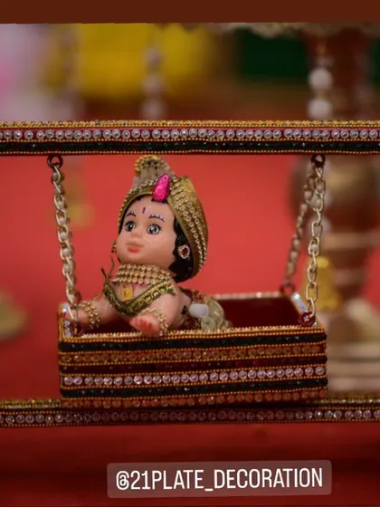 For a Naming Ceremony or cradle ceremony, I create these adorable doll arrangements. This close-up shows a beautifully decorated miniature cradle with a baby doll, a charming centerpiece for the celebration.