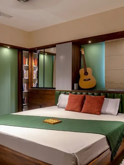 This bedroom features a dark wood bed with a green leather headboard and a custom niche for a guitar, reflecting the occupant's personality and hobbies.
