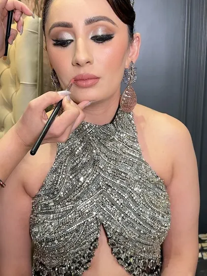 The final touch of a perfectly defined nude lip. This behind the scenes shot shows the precision required to create a flawless pout that completes the entire glamorous look.