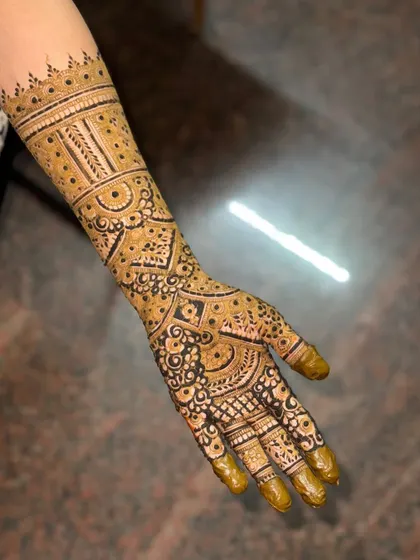 An elegant engagement henna design for one hand. The pattern is dense on the palm and transitions into beautiful bands on the forearm.