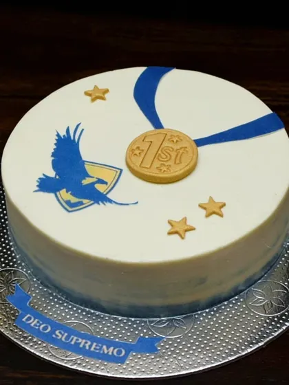 Celebrating a high school graduation with a custom cake. This design features the school's emblem and motto, along with a gold medal to commemorate the achievement.