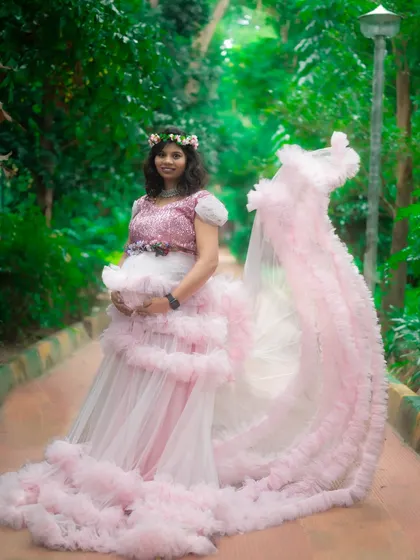 The long, flowing trail of this pink ruffle gown adds a touch of magic to this outdoor maternity shoot.