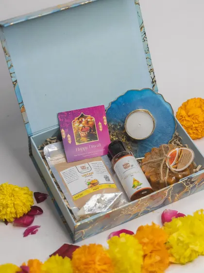 A stylish Diwali hamper in a blue marble-finish box. It contains our natural Ubtan powder, Abhyanga oil, handmade soap, and a beautiful resin art candle holder.