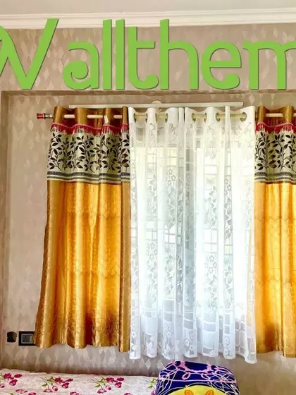 A close-up of a textured wallpaper installation in a bedroom, showing the clean finish around the window and curtains.