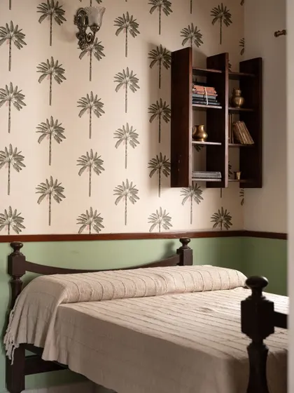 The matriarch's room in 'Varnika' has an earthy elegance, with a botanical wallpaper and a refurbished antique bed. The design feels rustic and tranquil.