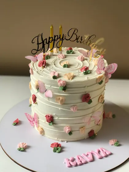 A white cake with a textured stripe design, decorated with small pink flowers and butterflies.