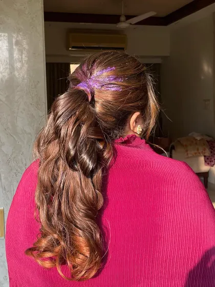 The purple glitter adds a pop of color and texture to the roots of this bouncy, curled ponytail. It’s a great way to add a personal touch to a classic style.
