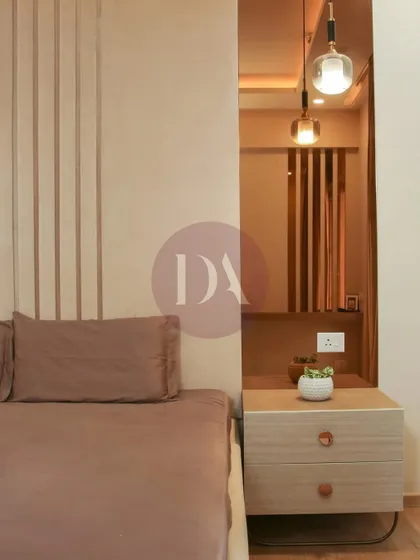 A close-up of a bedroom design focusing on texture and warmth. The fluted wall paneling behind the bed is complemented by a sleek wooden nightstand and a modern pendant light, creating a calm, contemporary feel.