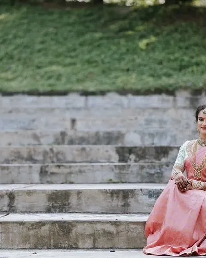 A wide shot showing the beautiful drape of the pastel pink Kanjeevaram against a simple, modern backdrop.